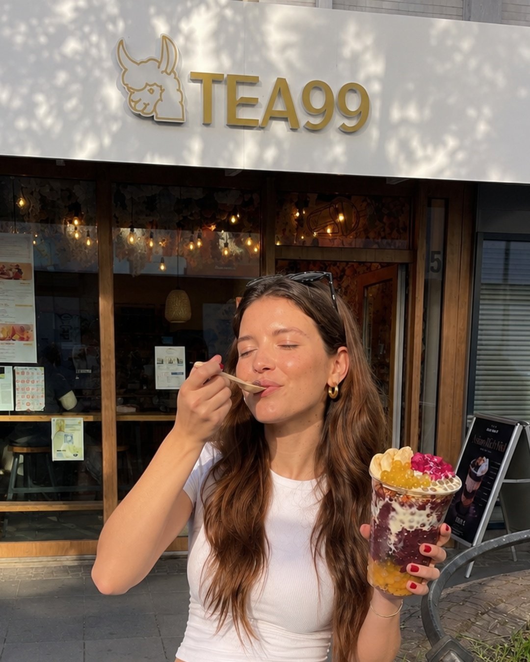 kundin genießt açaí bowl mit goldenem löffel vor tea99 storefront frankfurt — der purple moment